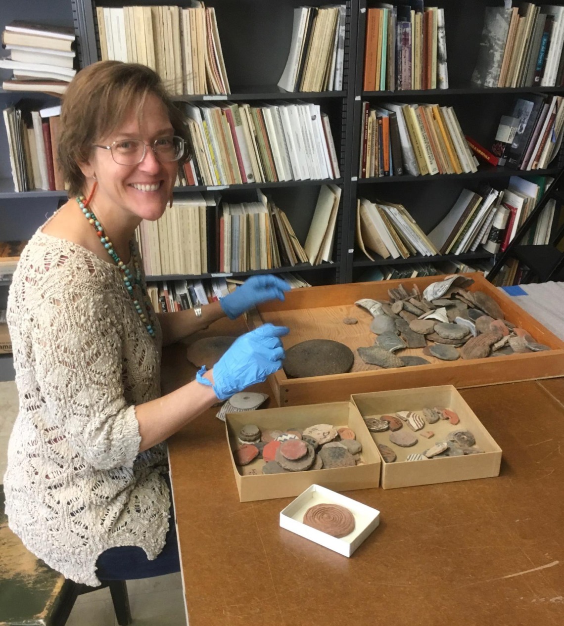 This is an image of Dr. Suzanne L. Eckert, head of collections. She is sorting pottery sherds.