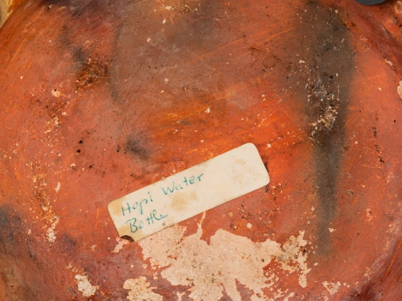 detail of 2016-21-3, showing a sticker that says, "Hopi water bottle," on the bottom of the vessel