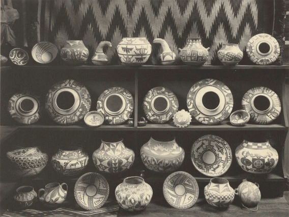 black and white photos showing rows of Hopi pottery lined up on shelves and on the floor