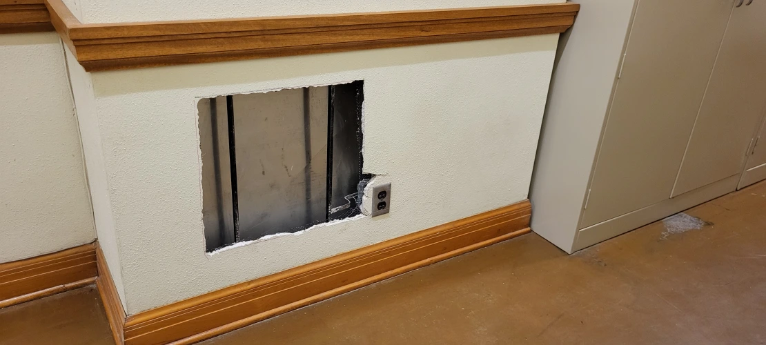 a hole cut in a hallway exposes ductwork behind the wall
