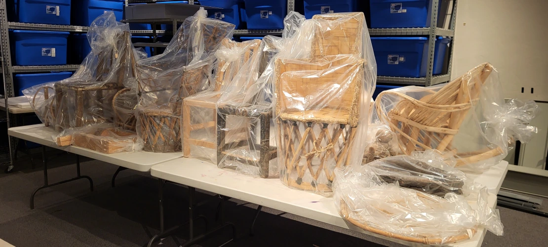 Large chairs, wrapped in plastic, are sitting on a table.