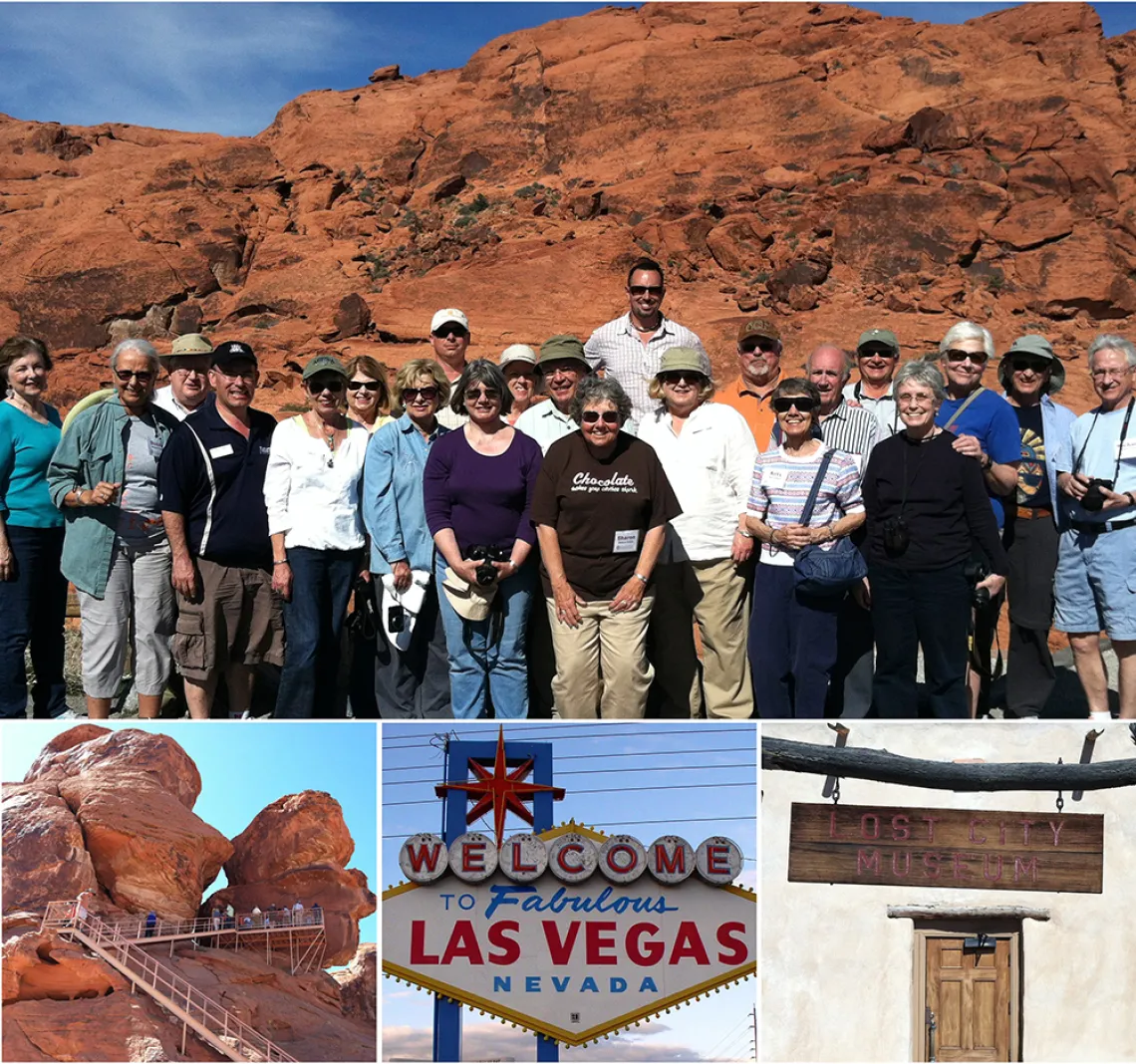 group of people smiling at the camera, standing in front of a red rock formation in the Mojave Desert.