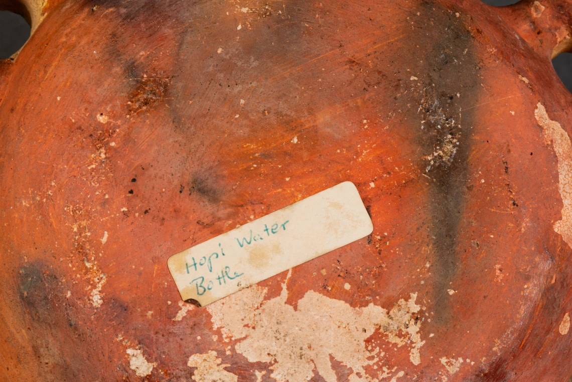 detail of 2016-21-3, showing a sticker that says, "Hopi water bottle," on the bottom of the vessel