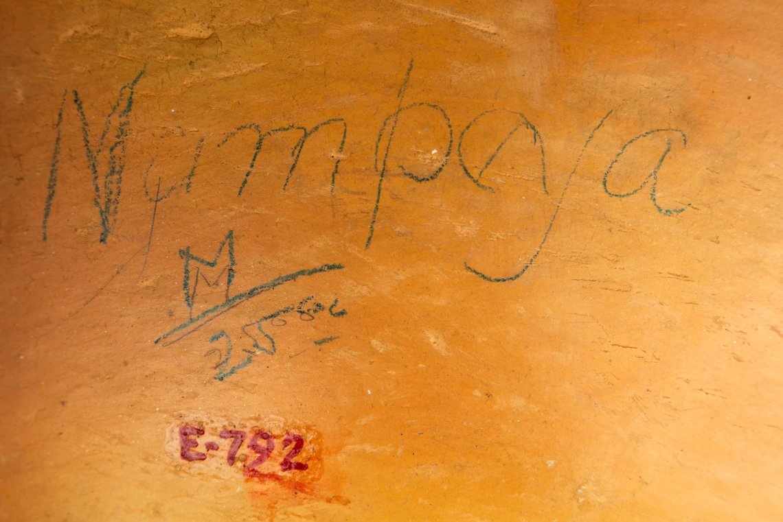 detail of E-792 showing Nampeyo's name written in pencil, along with “M 25.00,” on the side of the jar near the base