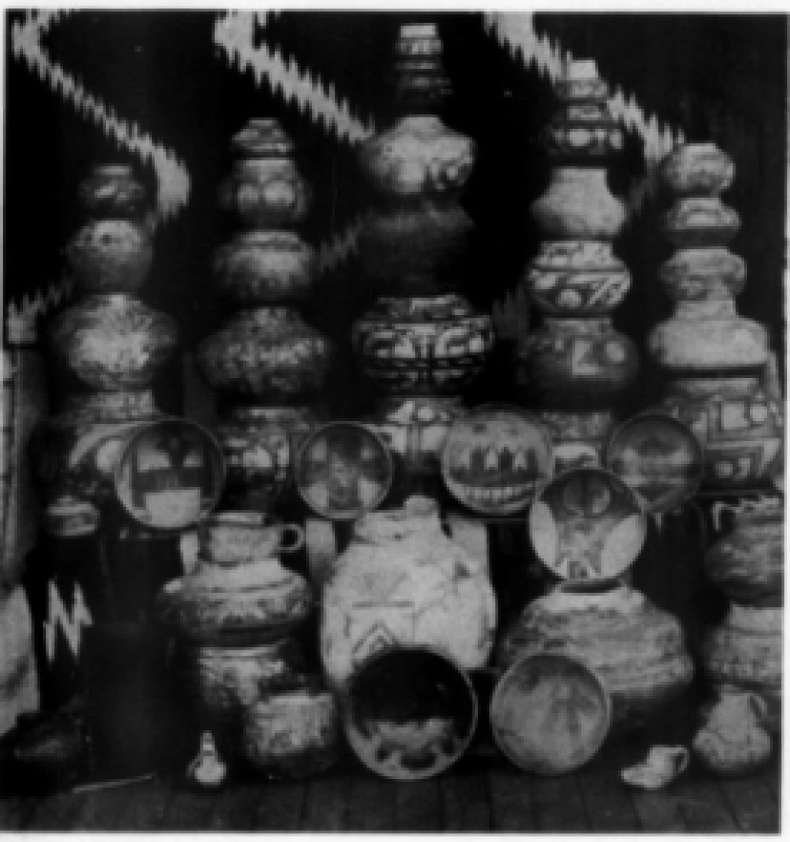 a very dark black and white image showing rows of pots, many stacked on each other