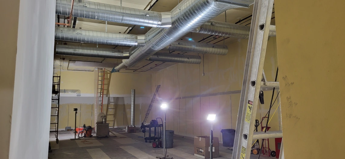 A room under renovation, showing installation of venting and electrical systems.