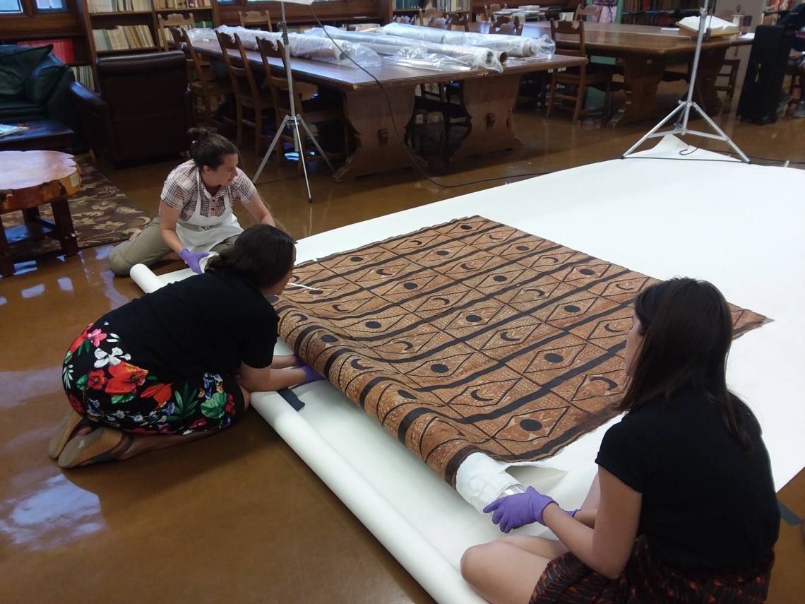 Conservators examining a tapa cloth made of mulberry bark