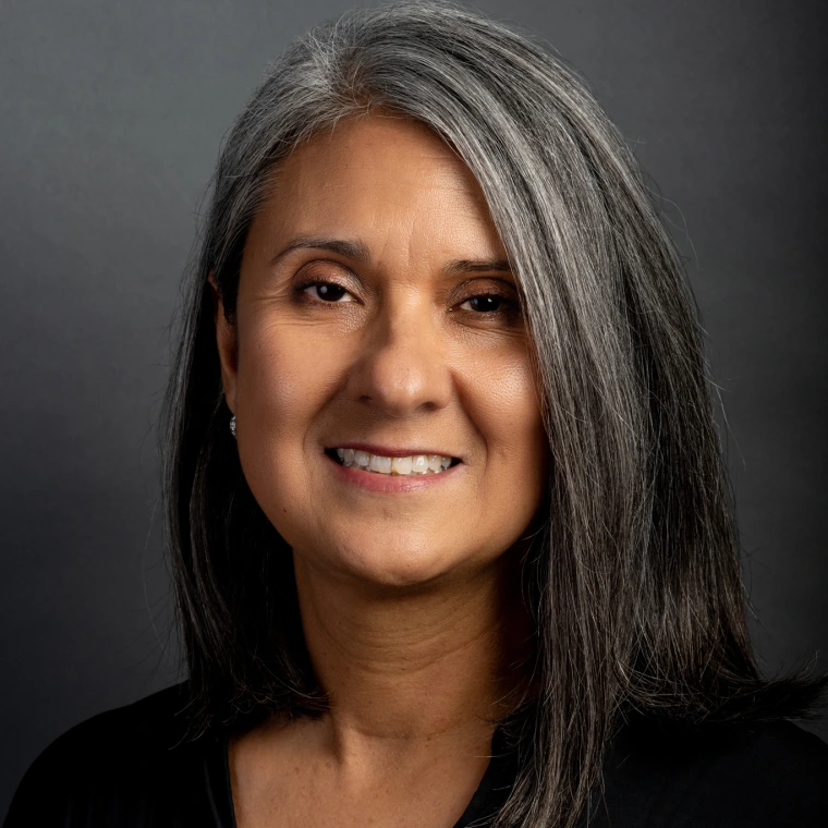 a woman with shoulder-length salt-and-pepper hair smiles into the camera