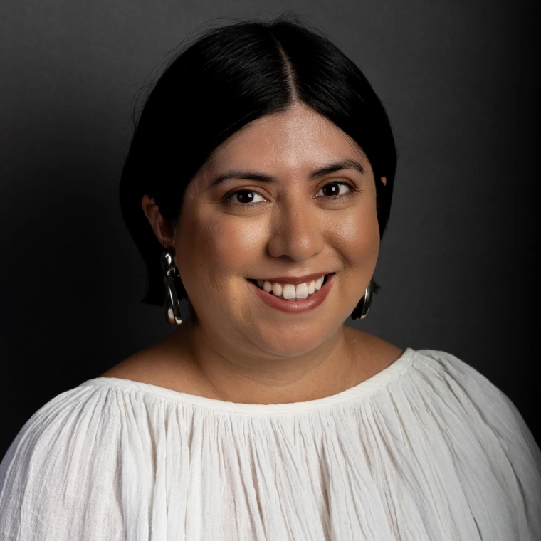 a young woman with dark short hair is wearing silver earrings and a white blouse