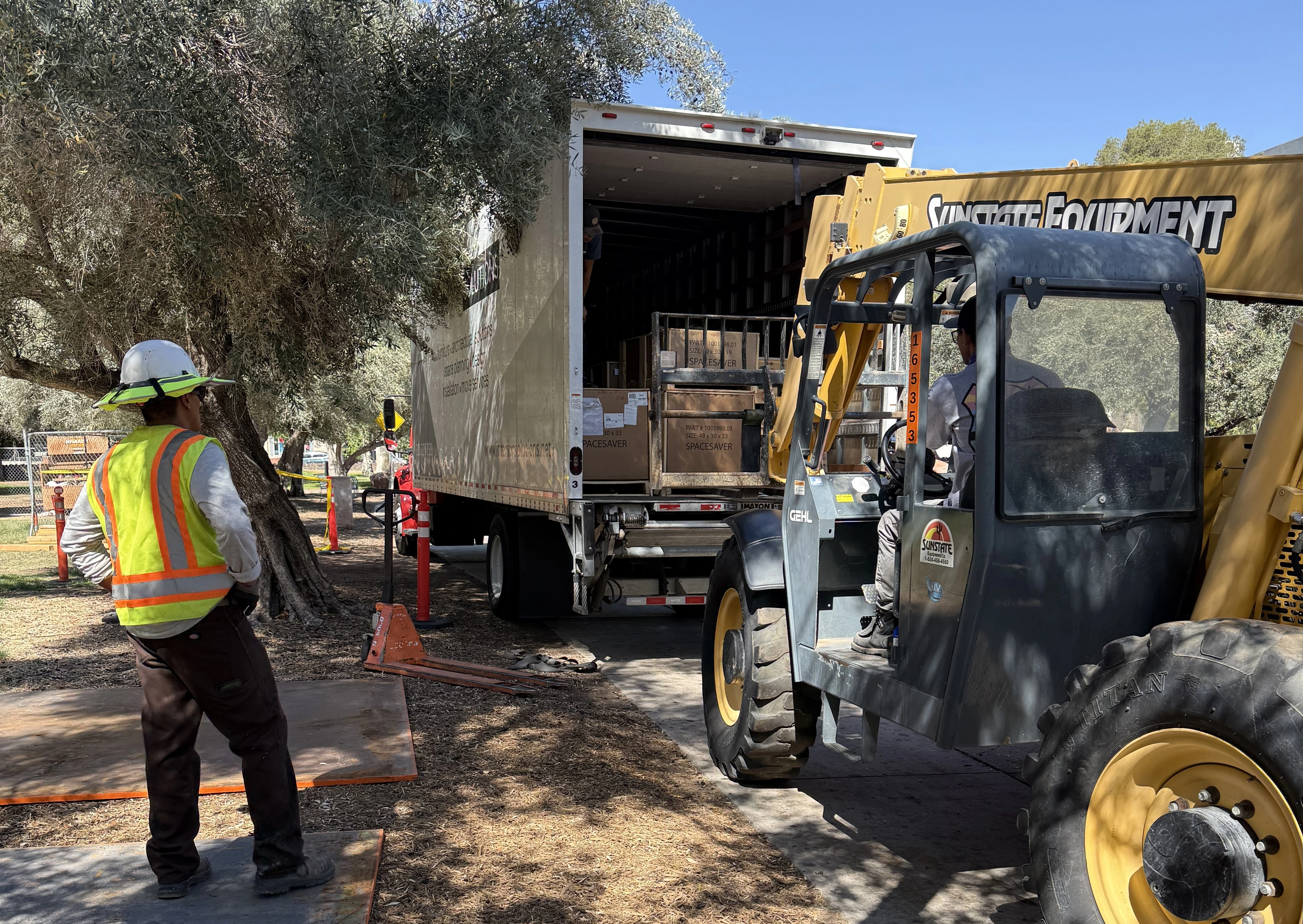 A box truck is parked at a curb with its tailgate up, ready to be unloaded.