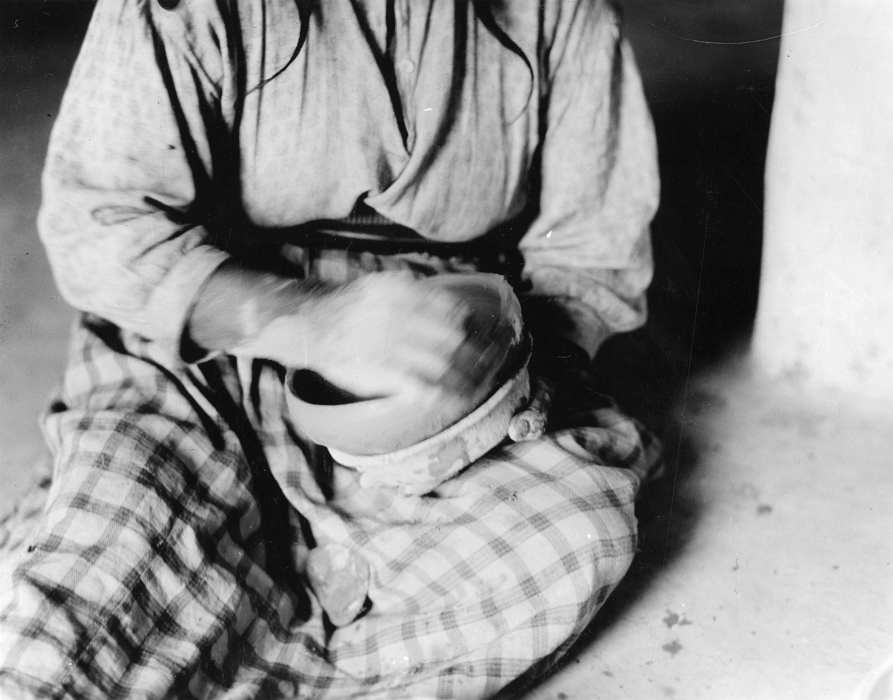 a woman smooths the side of a bowl she is hand building in clay