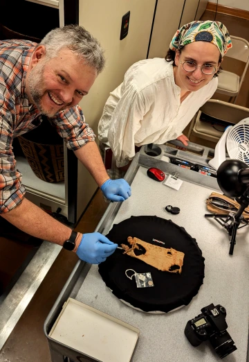 Two people examine and photograph an ancient sandal at Arizona State Museum.
