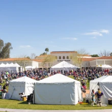 white tents and a lot of people on a green lawn